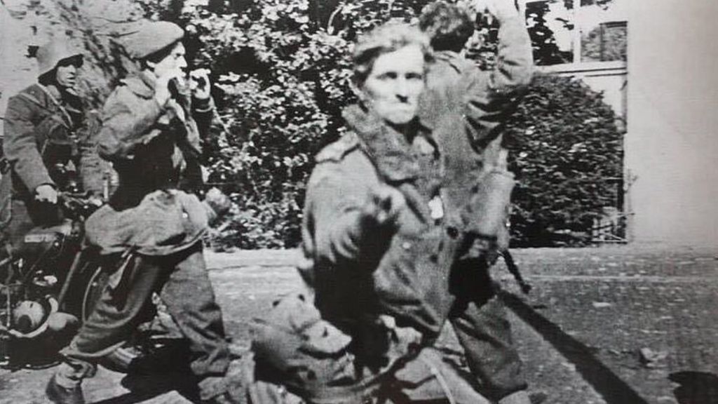 British soldier flicks V for Victory sign at German cameraman after capture.